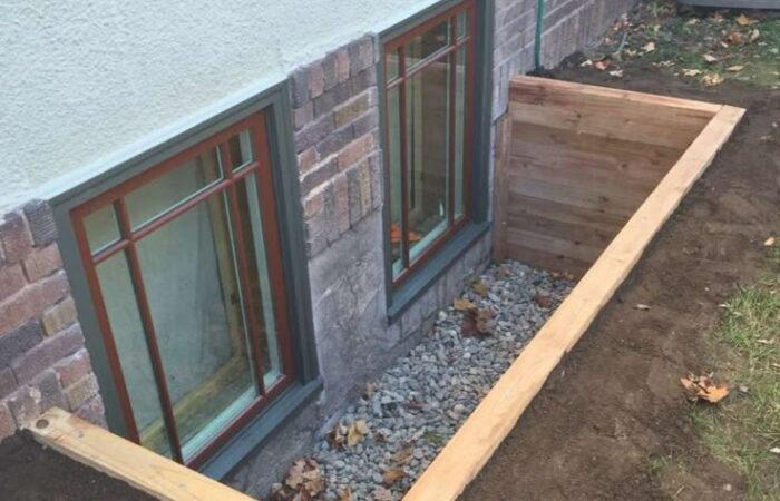 Wood-framed egress window well with gravel drainage
